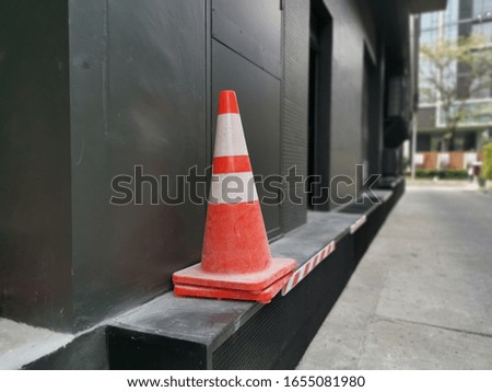 Traffic cone beside a black wall