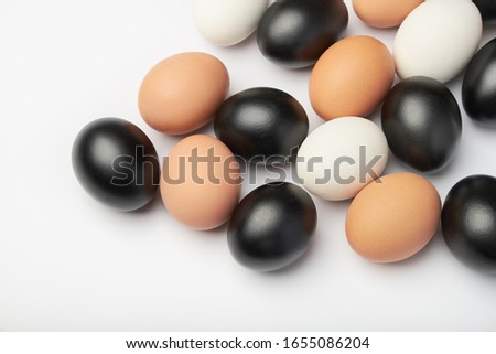 Many eggs of different colors on white background. Black, white and brown chicken eggs.