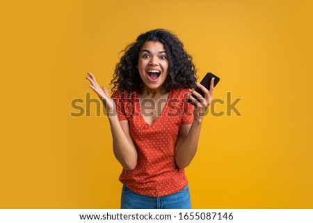 Amazed girl with mobile phone in hands celebrating victory in online casino, hitting jackpot in lotttery, making bets online at bookmaker's website. Female blogger happy to get one million followers.  Royalty-Free Stock Photo #1655087146