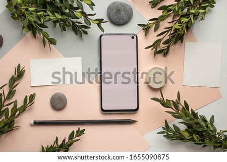 Workspace. Phone mockup, card mockup, pencil, rocks on grey and pink background. Overhead view. Flat lay, top view invitation card. copy space. palm leaves office or school mockup