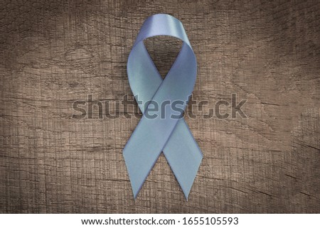 Blue ribbon on a wooden background.  The concept of cancer awareness. Empty text space