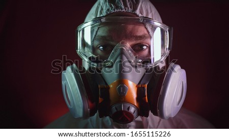 Man in protective costume suit, gas protect medical antibacterial antiviral spray paint mask. Doctor health worker in respirator. Concept health virus coronavirus epidemic. Radiation Nuclear war. Royalty-Free Stock Photo #1655115226