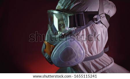 Man in protective costume suit, gas protect medical antibacterial antiviral spray paint mask. Doctor health worker in respirator. Concept health virus coronavirus epidemic. Radiation Nuclear war. Royalty-Free Stock Photo #1655115241