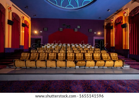 Large cinema theater interior with seat rows for audience to sit in movie theater premiere by cinematograph projector. The cinema theater is decorated in classical for luxury feel of movie watching. Royalty-Free Stock Photo #1655141596