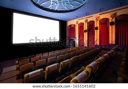 Cinema theater screen in front of seat rows in movie theater showing white screen projected from cinematograph. The cinema theater is decorated in classical style for luxury feeling of movie watching. Royalty-Free Stock Photo #1655141602