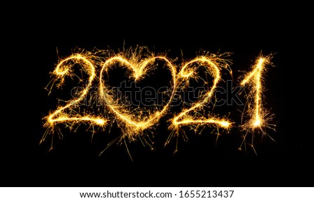 Happy New Year 2021. Creative Number 2021 with sign heart written sparkling sparklers isolated on black background for design. Beautiful Glowing overlay template for holiday greeting card. Royalty-Free Stock Photo #1655213437