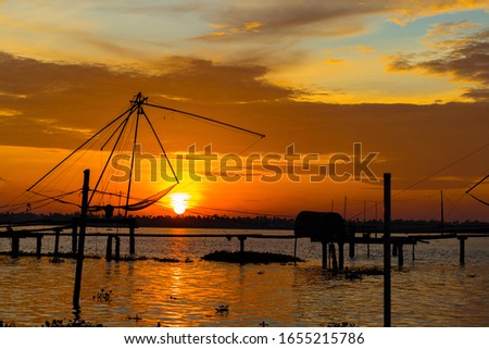 Warm sunset on the backwaters of Kumablangi, Cochin, India, with fishing nets on the foreground.