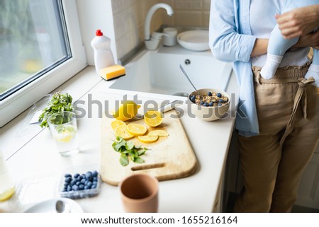 Smiling mother having useful breakfast while standing with her little child stock photo