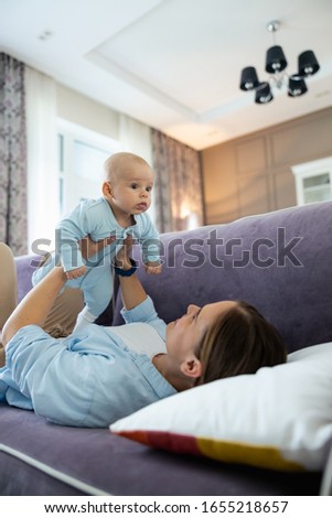Smiling beautiful mother spending time with her baby and having fun in living room stock photo