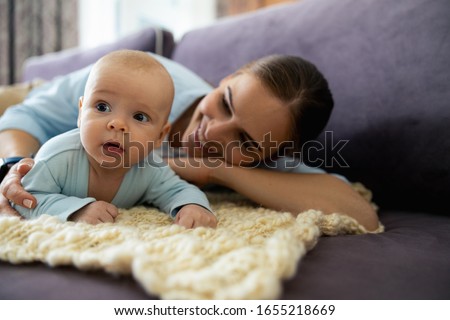 Happy pretty lady spending time with her little kid in living room stock photo