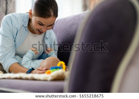 Smiling pretty mom spending time with her little kid in living room stock photo