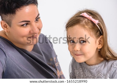 Emotional portrait of mom with daughter dressed in gray dress, on white background