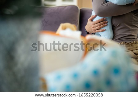 Cropped photo of mother sitting on bed with newborn baby in arms stock photo