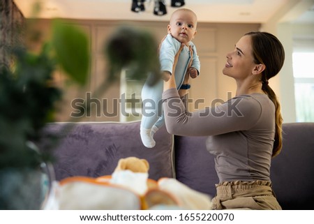 Smiling woman sitting on bed with newborn baby in arms stock photo