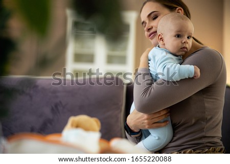 Smiling beautiful mom sitting on bed with newborn baby in arms stock photo