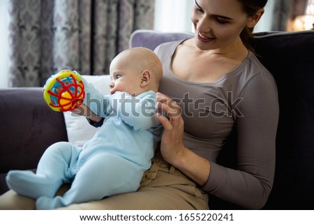 Smiling beautiful woman looking at her kid and enjoying time together at home stock photo