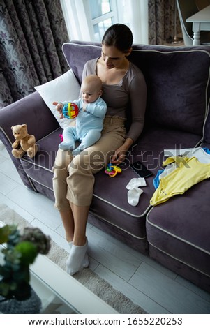 Happy beautiful lady looking at her kid and enjoying time together at home stock photo