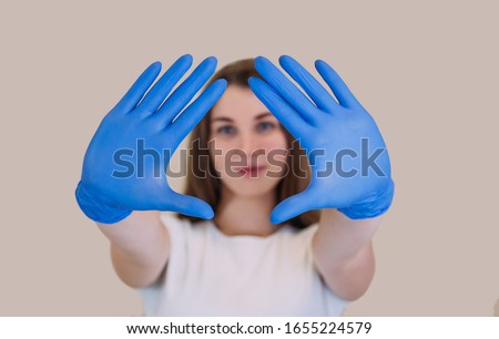 young beautiful girl in a white T-shirt in blue gloves, holds her arms extended forward