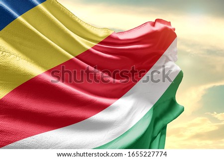 Seychelles national flag cloth fabric waving on the sky with beautiful sun light.