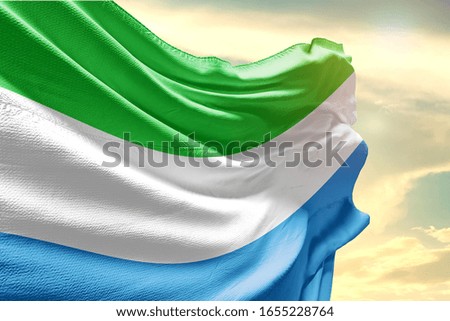 Sierra Leone national flag cloth fabric waving on the sky with beautiful sun light.