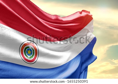 Paraguay national flag cloth fabric waving on the sky with beautiful sun light.