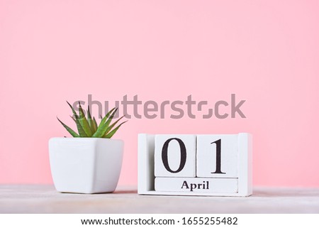Wooden blocks calendar with date 1st april and plant on pink background. April fools day concept Royalty-Free Stock Photo #1655255482