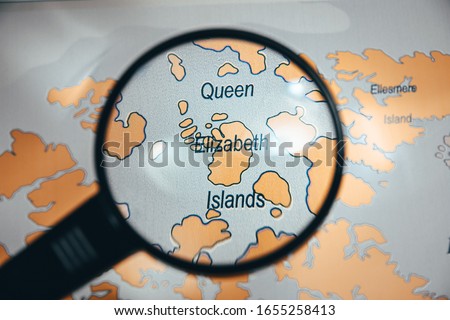 Queen Elizabeth Island in focus on world map through a black color magnify glass discover travel explore