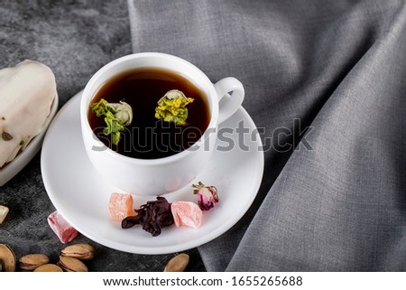 A cup of tea with nuts, Turkish lokum and flower blossoms