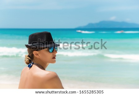 Woman in black hat relaxing at beautiful tropical beach. copy space, banner. Summer holidays concept