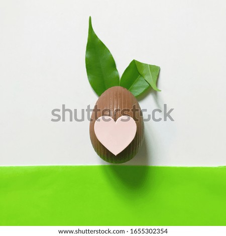 Happy Easter. Minimal Easter concept: chocolate egg and rabbit ears made from fresh leaves