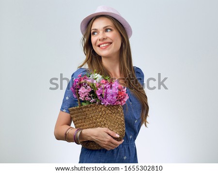 smiling woman wearing cassual blue dress holding flowers looking at side away. 