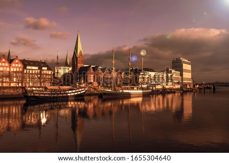 Three masters are located on the Weser promenade in Bremen and are reflected in the water at dusk