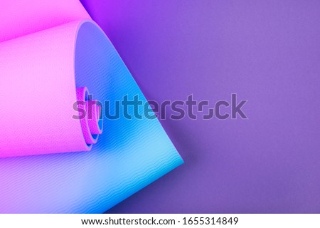 Top view of neon colored blue pink yoga mat on violet background. Yoga pilates sport concept. Flat Lay. 