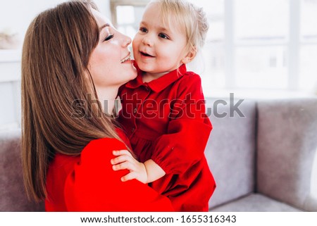 Mother smiles and kisses her daughter. A happy family. Portrait of a mother.