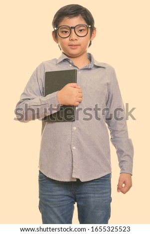 Studio shot of cute Japanese boy holding book
