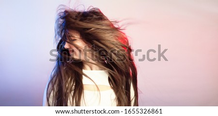 Woman with fluttering hair on colored studio background, teenager emotion protest, girl fooling around