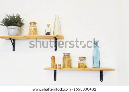 Decorative shelves on white brick wall with vintage bottles and wicker jars on it