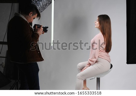Young beautiful model posing for professional photographer in studio.