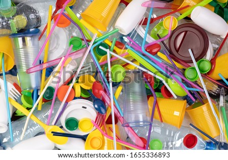 Disposable single use plastic objects such as bottles, cups, forks, spoons and drinking straws that cause pollution of the environment, especially oceans. Top view. Royalty-Free Stock Photo #1655336893