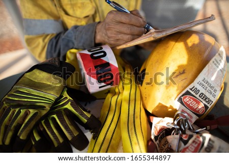 Rigger inspector high risk worker   inspecting checking yellow three lifting sling with red danger tag safety glove personal lock tags helmet prior used construction building site, Australia 
 Royalty-Free Stock Photo #1655344897