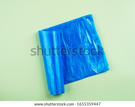 Blue plastic garbage bag roll on green background. Plastic recycling concept