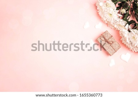 Bouquet of chrysanthemums and gift box on a pink background. Copy space, top view.