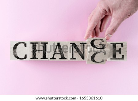 hand turning word CHANGE into CHANCE on wooden blocks against pink background