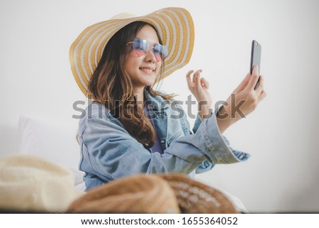 pretty woman traveler shooting selfie and choosing fashion hat prepare packing clothes into suitcase for holiday vacation at home, long weekend, summer holiday, vacation, backpacker and travel concept
