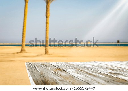 Wooden table of free space for your decoration and blurred landscape with palms.Copy space for your products.