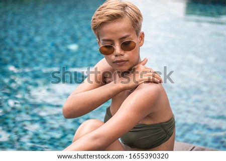 Close up portrait of young attractive woman applying sunscreen near swimming pool stock photo