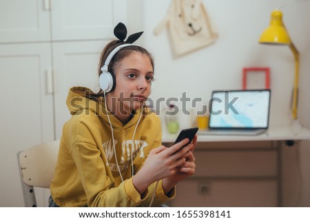 young girl sitting desk at her room, using mobile phone