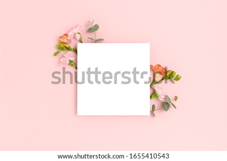 Blank paper card mockup with frame made of flowers and eucalyptus. Festive floral composition with copy space on a pink pastel background. Royalty-Free Stock Photo #1655410543