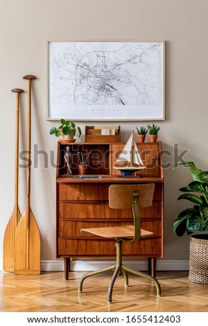 Stylish and vintage interior design of living room with wooden retro commode, plants, ships, paddle, map and elegant personal accessories. Mock up poster frame on the wall. Template. Home decor.