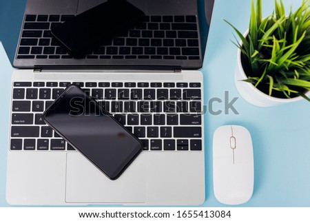 Top view of modern technology smart phone mobile and computer laptop on blue background with copy space